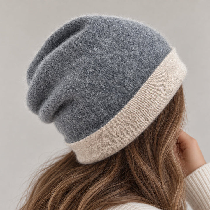A person wearing a slouchy knit beanie hat with a heathered gray top and a contrasting cream brim, shown from the back against a soft light gray background.