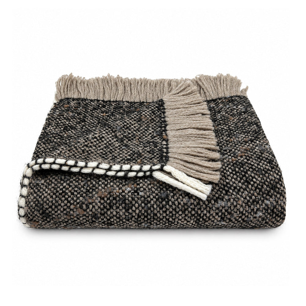 A folded woven alpaca blend throw blanket with a textured black and beige pattern, featuring a thick beige fringe trim and a white-and-black braided edge, shown on a plain white background.