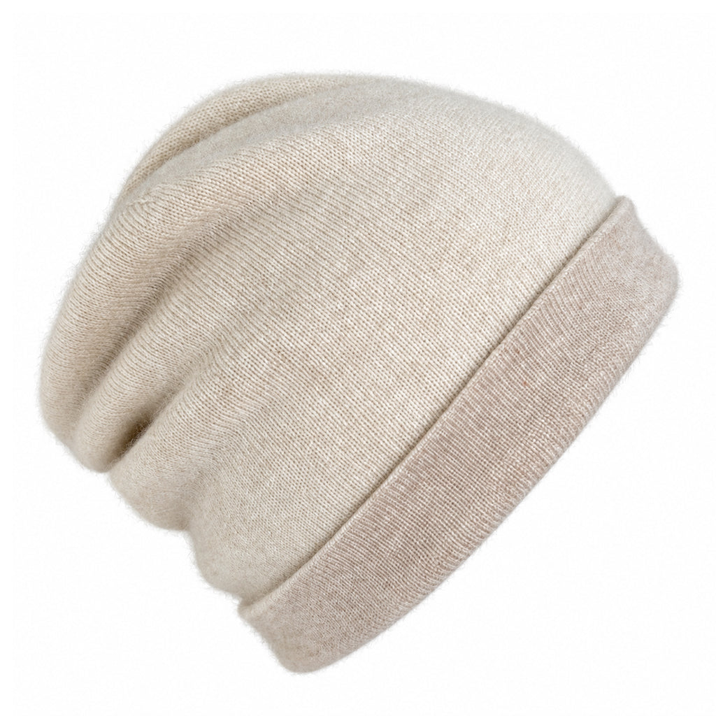 A slouchy knit beanie hat in a light cream or oatmeal color, featuring a ribbed fold-over cuff, shown against a plain white background.