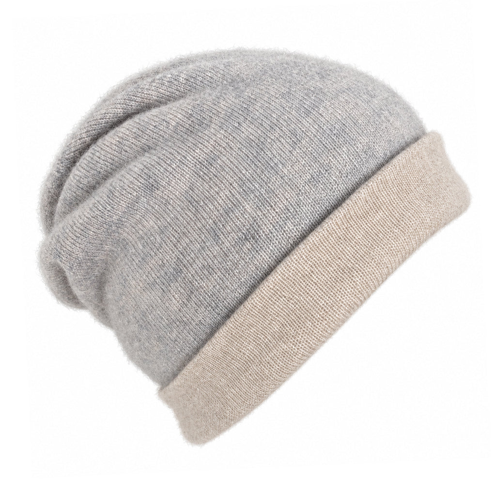 A slouchy knit cashmere beanie featuring a heathered light gray main body and a contrasting solid beige ribbed cuff, shown on a plain white background.