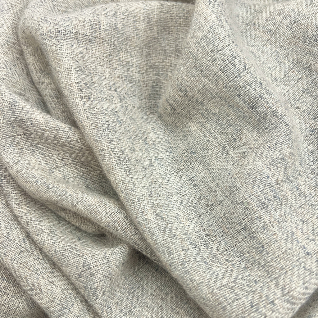 A close-up of draped light gray heathered fabric with a soft, textured weave.