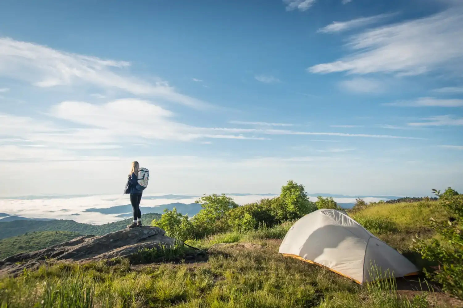 Hiker standing on a rocky outcrop overlooking a scenic landscape.